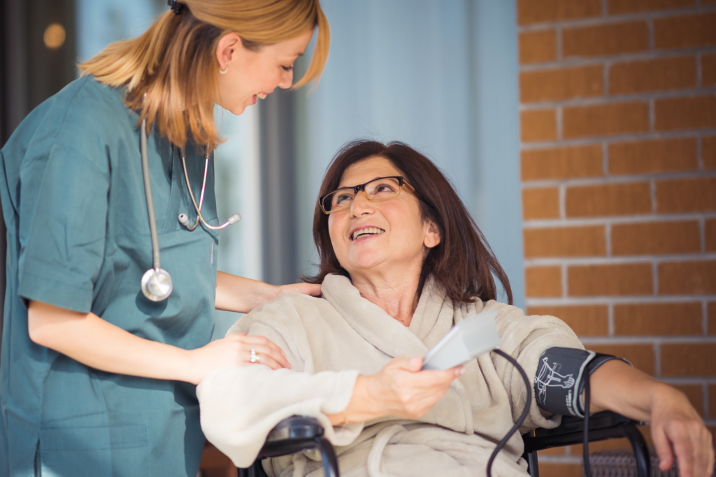A nurse assists an elderly woman in a wheelchair, providing support and care in a healthcare setting.
