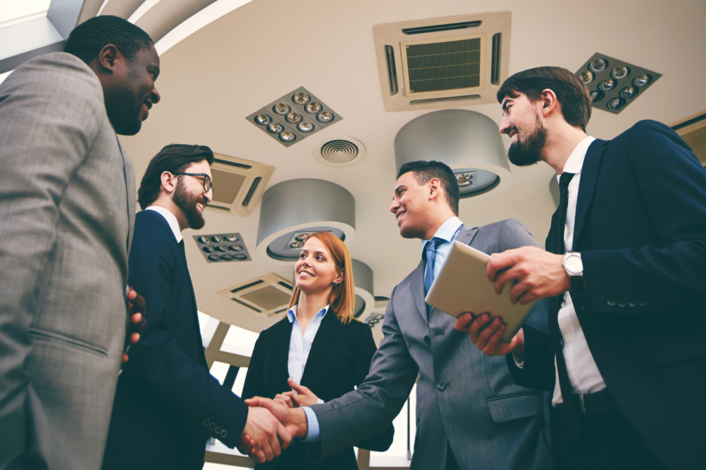 Business professionals shaking hands in a modern office setting, symbolizing agreement and collaboration.